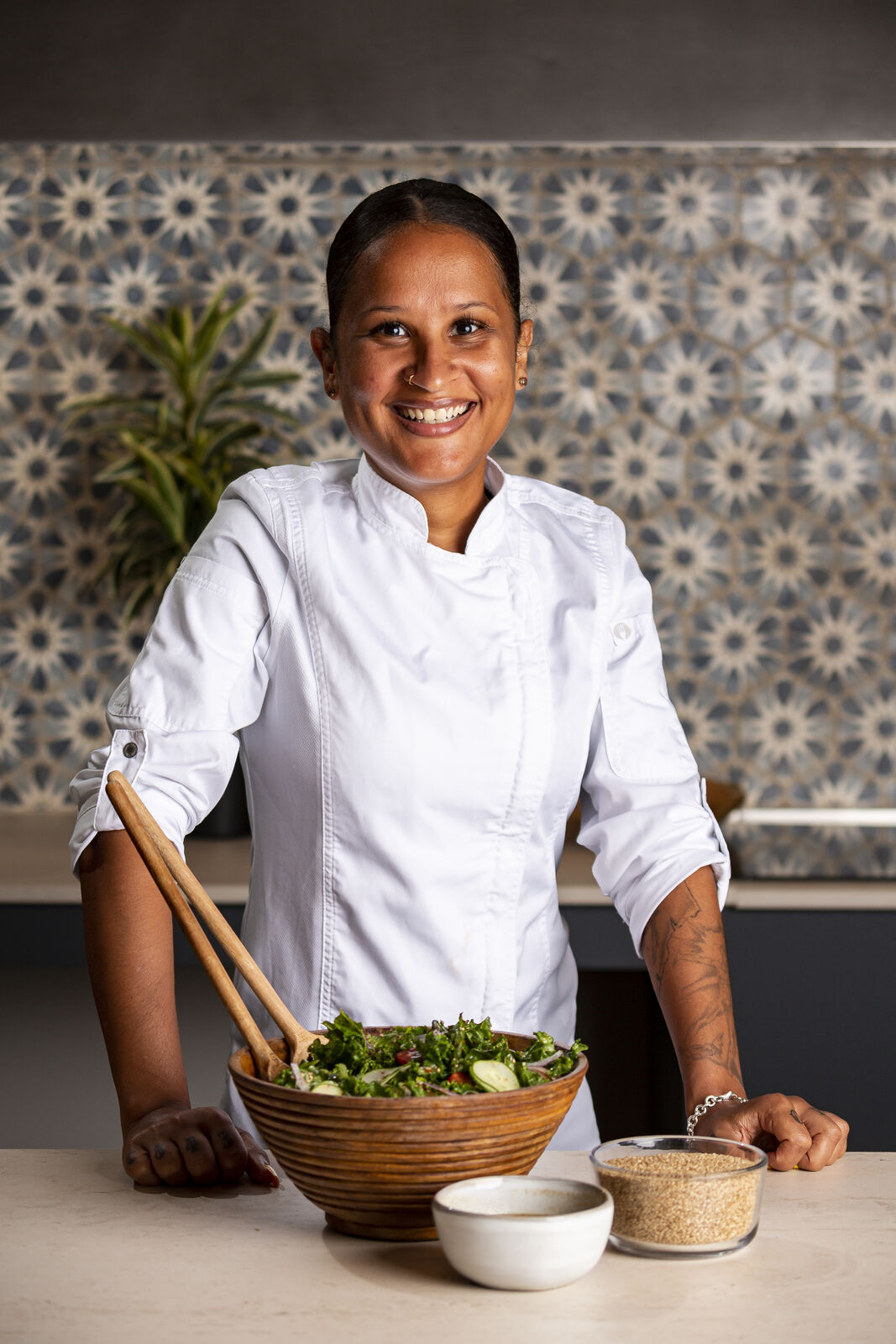 Chef smiling with salad bowl and ingredients on the counter.